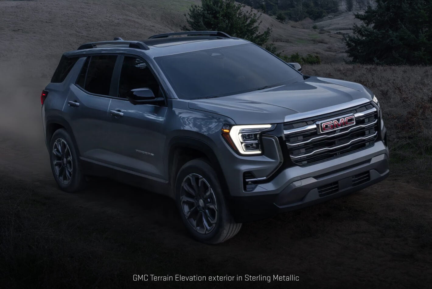 GMC Terrain Elevation in Sterling Metallic showcasing its athletic stance kicking up dust along a winding dirt path.