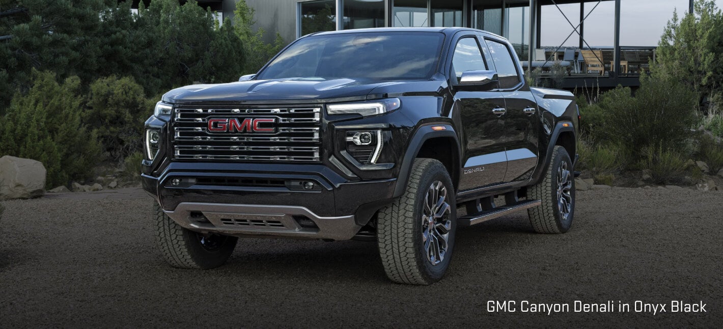 GMC Canyon Denali exterior in Onyx Black showing a front three-quarters view parked on a gravel driveway.