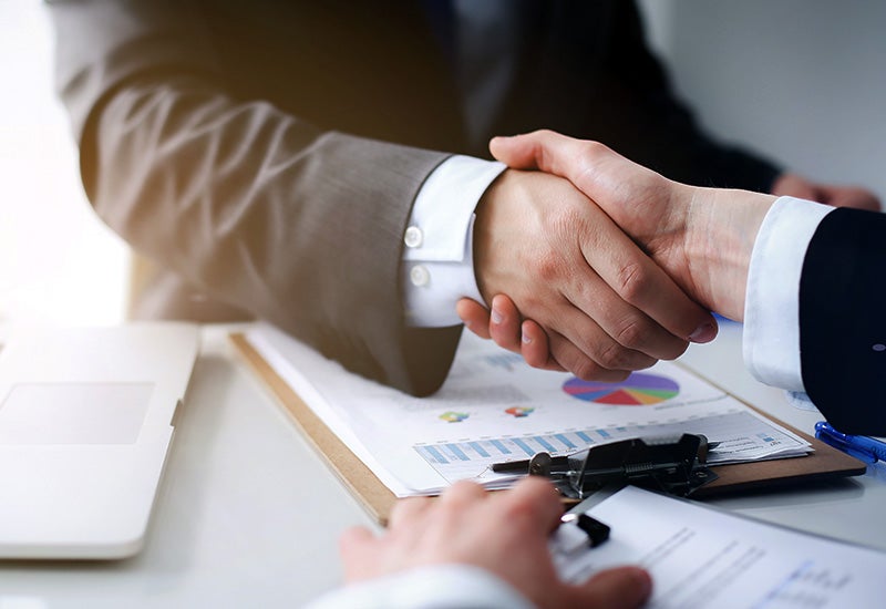 Business handshake over financial paperwork
